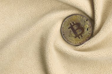 Altın bitcoin yumuşak ve kabarık ışık turuncu Polar kumaş çok sayıda kabartma kıvrımları ile yapılmış bir battaniye yatıyor. Kıvrımları şeklinde bir ekran kartı soğutucu fan benzer