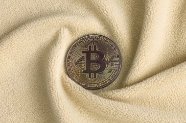 Altın bitcoin yumuşak ve kabarık ışık turuncu Polar kumaş çok sayıda kabartma kıvrımları ile yapılmış bir battaniye yatıyor. Kıvrımları şeklinde bir ekran kartı soğutucu fan benzer