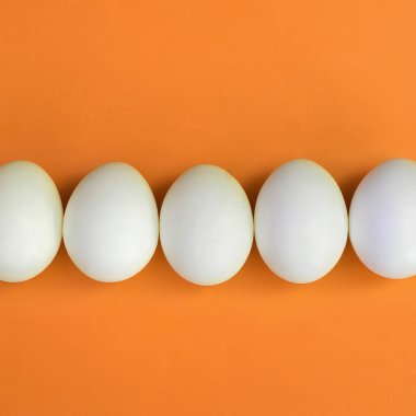 Bir kaç beyaz Paskalya yumurtaları parlak turuncu zemin