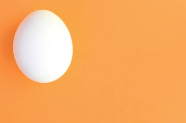 Parlak turuncu arka plan üzerinde beyaz bir Paskalya yortusu yumurta