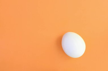 Parlak turuncu arka plan üzerinde beyaz bir Paskalya yortusu yumurta