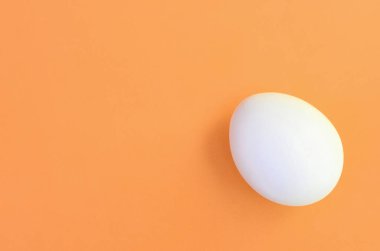 Parlak turuncu arka plan üzerinde beyaz bir Paskalya yortusu yumurta