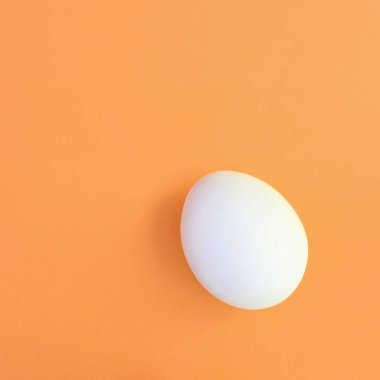 Parlak turuncu arka plan üzerinde beyaz bir Paskalya yortusu yumurta