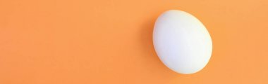 Parlak turuncu arka plan üzerinde beyaz bir Paskalya yortusu yumurta