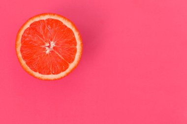 Hafif pembe renkte parlak arka plan üzerinde üstten görünüm bir bir greyfurt dilim. Doymuş narenciye doku görüntü