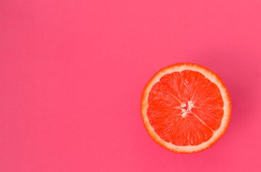 Hafif pembe renkte parlak arka plan üzerinde üstten görünüm bir bir greyfurt dilim. Doymuş narenciye doku görüntü