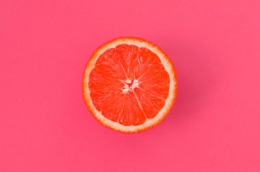 Hafif pembe renkte parlak arka plan üzerinde üstten görünüm bir bir greyfurt dilim. Doymuş narenciye doku görüntü