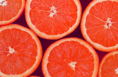 Pembe renkte parlak arka plan üzerinde üstten görünüm birkaç greyfurt dilim. Doymuş narenciye doku görüntü