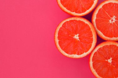 Pembe renkte parlak arka plan üzerinde üstten görünüm birkaç greyfurt dilim. Doymuş narenciye doku görüntü
