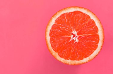 Hafif pembe renkte parlak arka plan üzerinde üstten görünüm bir bir greyfurt dilim. Doymuş narenciye doku görüntü