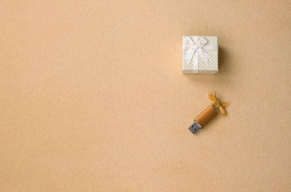Оранжевый USB карта памяти с луком лежит рядом с небольшой подарочной коробке в оранжевом с небольшим луком на одеяло из мягкой и пушистой легкой ткани шерсти. Классический дизайн карты памяти подарок — стоковое фото