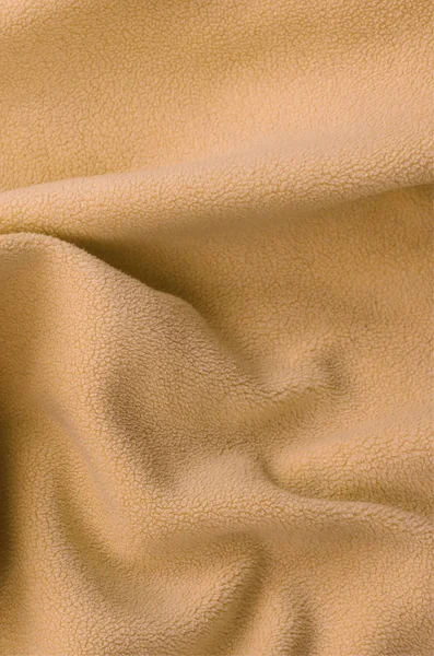 The blanket of furry orange fleece fabric. A background of light orange soft plush fleece material with a lot of relief folds