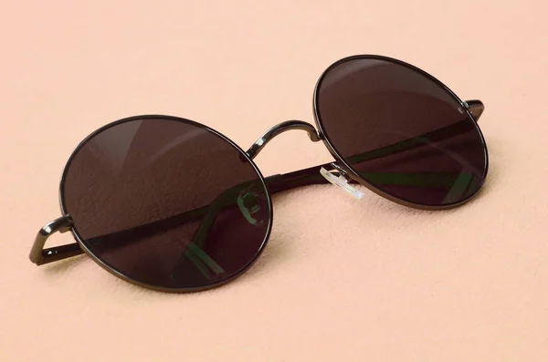 Die stylische schwarze Sonnenbrille mit runder Brille liegt auf einer Decke aus weichem und flauschigem hellorangefarbenem Fleece-Stoff. modisches Hintergrundbild in modischen Farben — Stockfoto