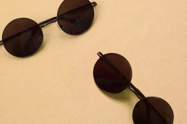 Två snygga svarta solglasögon med runda glasögon ligger på en filt tillverkad av mjuk och fluffig ljus orange fleecetyg. Fashionabla bakgrundsbild i mode färger — Stockfoto