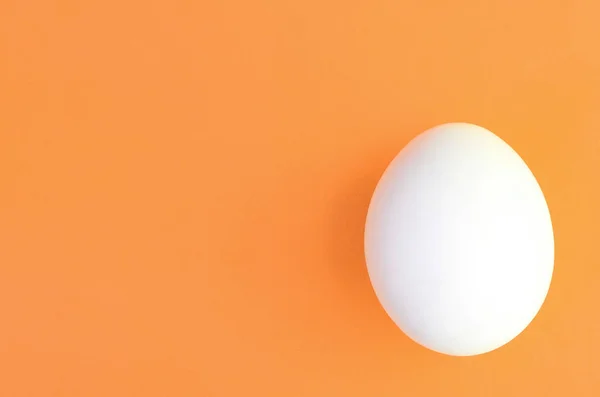 Un oeuf de Pâques blanc sur un fond orange vif — Photo