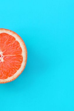 Mavi renkte parlak arka plan üzerinde üstten görünüm bir greyfurt dilim. Doymuş narenciye doku görüntü