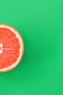 Yeşil renkli parlak arka plan üzerinde üstten görünüm bir greyfurt dilim. Doymuş narenciye doku görüntü
