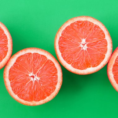 Yeşil renkli parlak arka plan üzerinde üstten görünüm birkaç greyfurt dilim. Doymuş narenciye doku görüntü