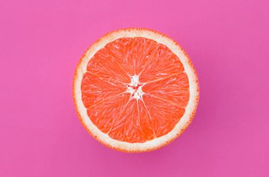 Mor renkli parlak arka plan üzerinde üstten görünüm bir greyfurt dilim. Doymuş narenciye doku görüntü