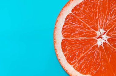 Mavi renkte parlak arka plan üzerinde üstten görünüm bir greyfurt dilim. Doymuş narenciye doku görüntü