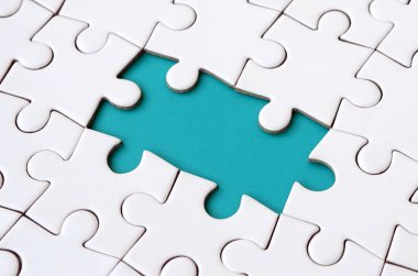 Beyaz jigsaw bulmaca monte durumunda eksik öğeleri metin için mavi bir ped şekillendirme ile yakın çekim doku. Kopya alanı