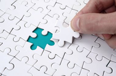 The human hand fills the last missing elements of the surface from the jigsaw puzzle. The concept of the completion of the initiated cases clipart