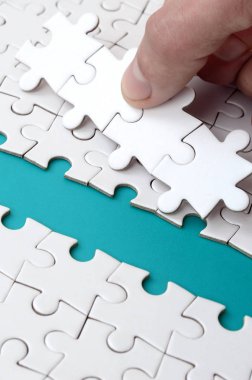 İnsan eli jigsaw bulmaca, mavi bir alan oluşturan yüzeye yol açıyor. Başarı için yolda zorluklar üstesinden kavramı