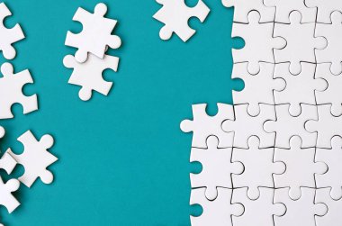 Katlanmış bir beyaz jigsaw puzzle ve bir yığın uncombed bulmaca öğeleri arka planı mavi bir yüzey parçası. Metin için yer ile doku fotoğraf