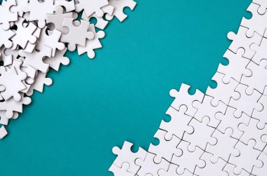 Katlanmış bir beyaz jigsaw puzzle ve bir yığın uncombed bulmaca öğeleri arka planı mavi bir yüzey parçası. Metin için yer ile doku fotoğraf