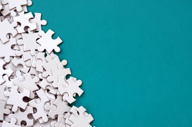 Bir yığın beyaz jigsaw puzzle uncombed unsurlarının mavi bir yüzey arka plan üzerinde yatıyor. Metin kopyalama yeri olan doku fotoğraf