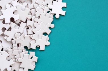 Bir yığın beyaz jigsaw puzzle uncombed unsurlarının mavi bir yüzey arka plan üzerinde yatıyor. Metin kopyalama yeri olan doku fotoğraf
