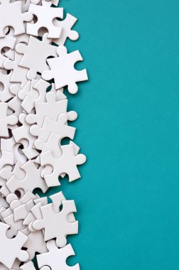 Bir yığın beyaz jigsaw puzzle uncombed unsurlarının mavi bir yüzey arka plan üzerinde yatıyor. Metin kopyalama yeri olan doku fotoğraf