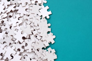 Bir yığın beyaz jigsaw puzzle uncombed unsurlarının mavi bir yüzey arka plan üzerinde yatıyor. Metin kopyalama yeri olan doku fotoğraf