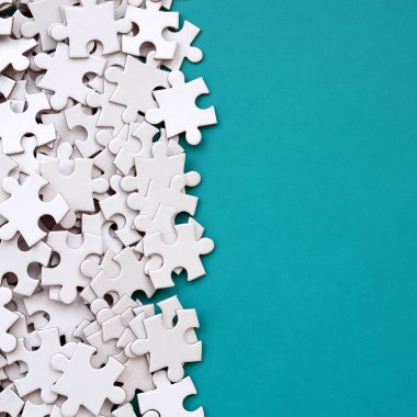 Bir yığın beyaz jigsaw puzzle uncombed unsurlarının mavi bir yüzey arka plan üzerinde yatıyor. Metin kopyalama yeri olan doku fotoğraf
