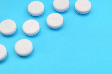 Bir kaç beyaz tabletler bir parlak mavi arka plan yüzeye yalan. İlaç ve tıbbi konularda arka plan görüntüsü