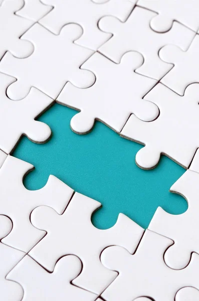 Struttura ravvicinata di un puzzle bianco in stato assemblato con elementi mancanti che formano un pad blu per il testo. Copia spazio — Foto Stock