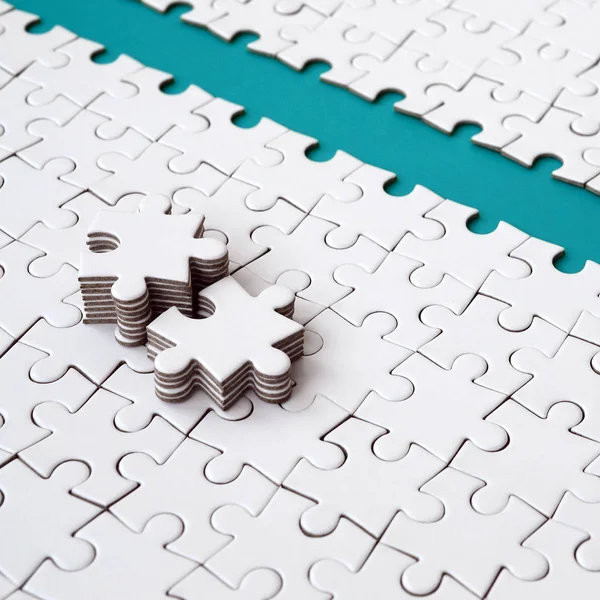 The blue path is laid on the platform of a white folded jigsaw puzzle. The missing elements of the puzzle are stacked nearby. Texture image with space for text