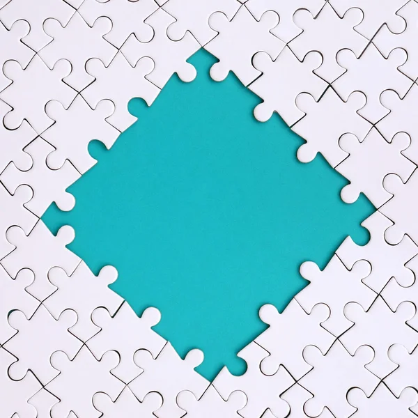 Emoldurando na forma de um losango, feito de um quebra-cabeça branco em torno do espaço azul — Fotografia de Stock