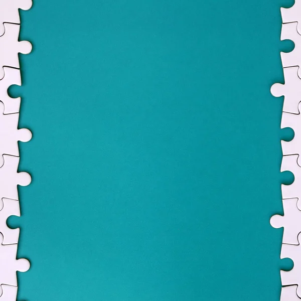 Фрагмент складеної білої головоломки на тлі синьої пластикової поверхні. Текстура фотографії з простором копіювання для тексту — стокове фото