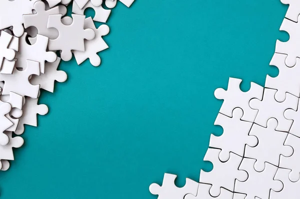 Katlanmış bir beyaz jigsaw puzzle ve bir yığın uncombed bulmaca öğeleri arka planı mavi bir yüzey parçası. Metin için yer ile doku fotoğraf