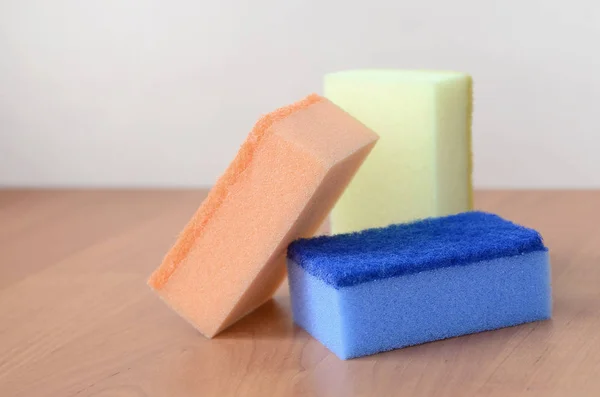 A few kitchen sponges lie on a wooden kitchen countertop. Colorf