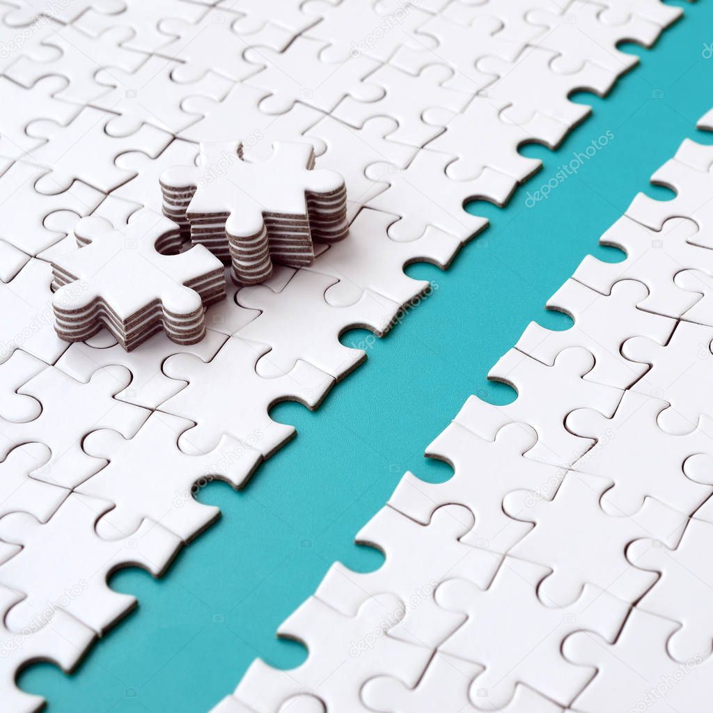 The blue path is laid on the platform of a white folded jigsaw puzzle. The missing elements of the puzzle are stacked nearby. Texture image with space for text