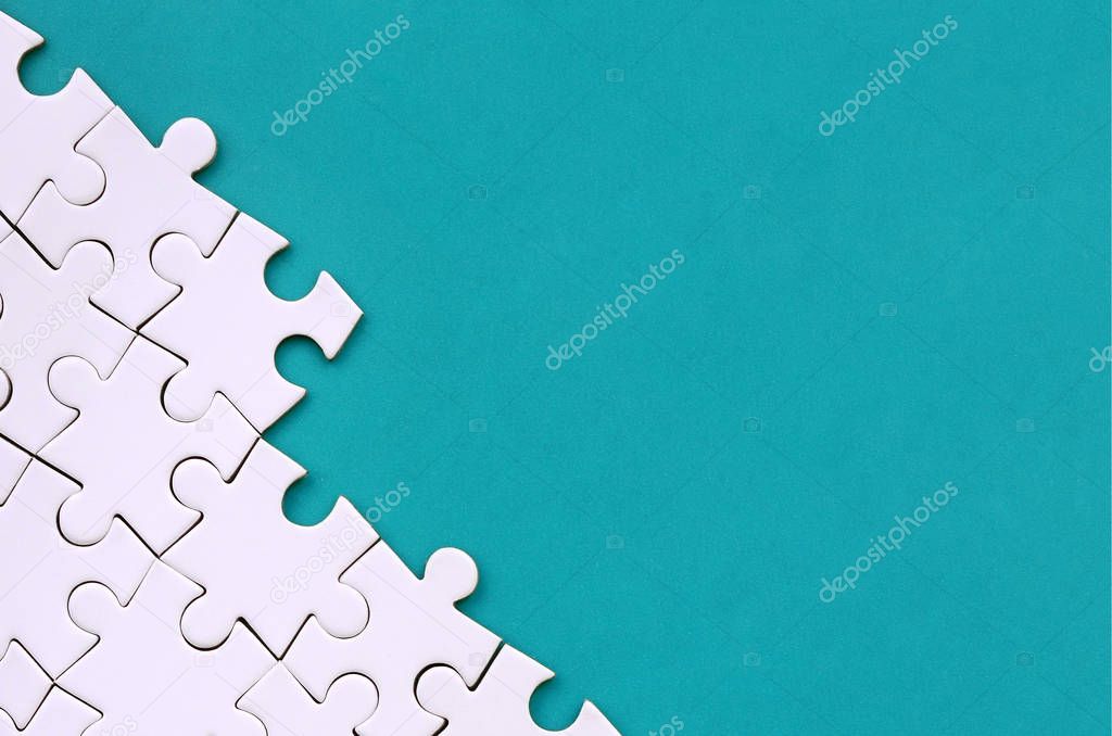 Fragment of a folded white jigsaw puzzle on the background of a blue plastic surface. Texture photo with copy space for text