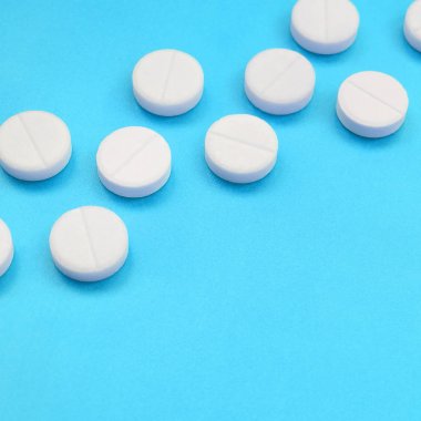 Bir kaç beyaz tabletler bir parlak mavi arka plan yüzeye yalan. İlaç ve tıbbi konularda arka plan görüntüsü