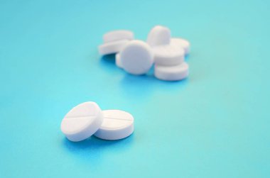 Bir kaç beyaz tabletler bir parlak mavi arka plan yüzeye yalan. İlaç ve tıbbi konularda arka plan görüntüsü