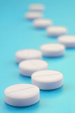 Bir kaç beyaz tabletler bir parlak mavi arka plan yüzeye yalan. İlaç ve tıbbi konularda arka plan görüntüsü