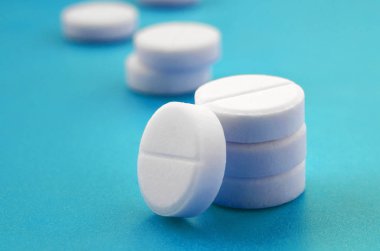 Bir kaç beyaz tabletler bir parlak mavi arka plan yüzeye yalan. İlaç ve tıbbi konularda arka plan görüntüsü