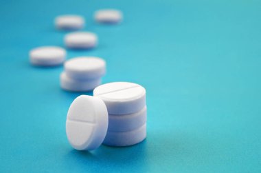 Bir kaç beyaz tabletler bir parlak mavi arka plan yüzeye yalan. İlaç ve tıbbi konularda arka plan görüntüsü