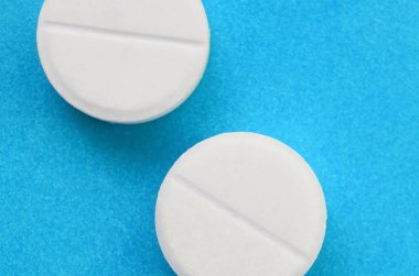 Bir kaç beyaz tabletler bir parlak mavi arka plan yüzeye yalan. İlaç ve tıbbi konularda arka plan görüntüsü