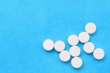 Birkaç beyaz tabletler parlak mavi bir arka plan bir bakteri şeklinde yalan. Tıp ve eczacılık konularda arka plan görüntüsü